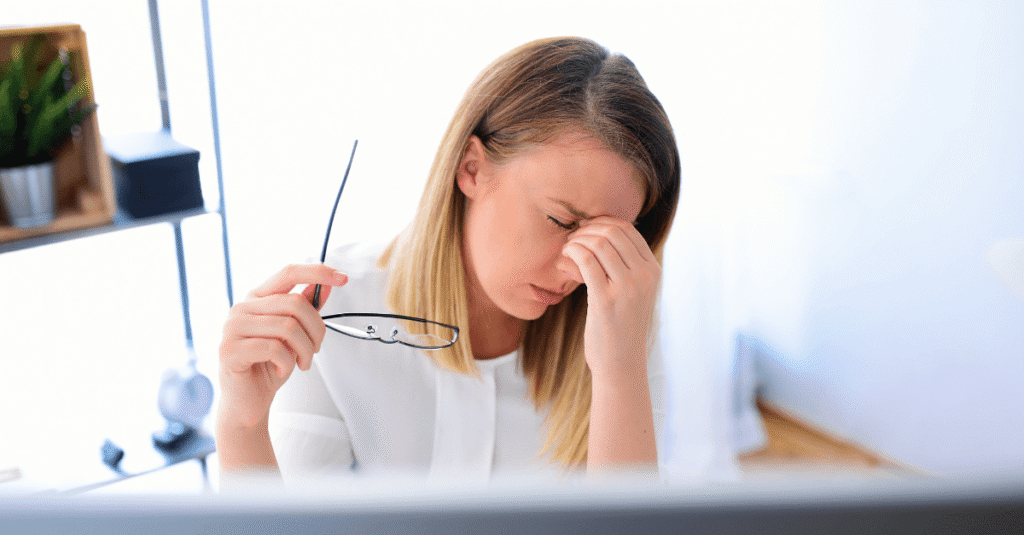 A women who took her glasses of and holding it in her right hand. With her left hand she is irritated scratching her eyes.
